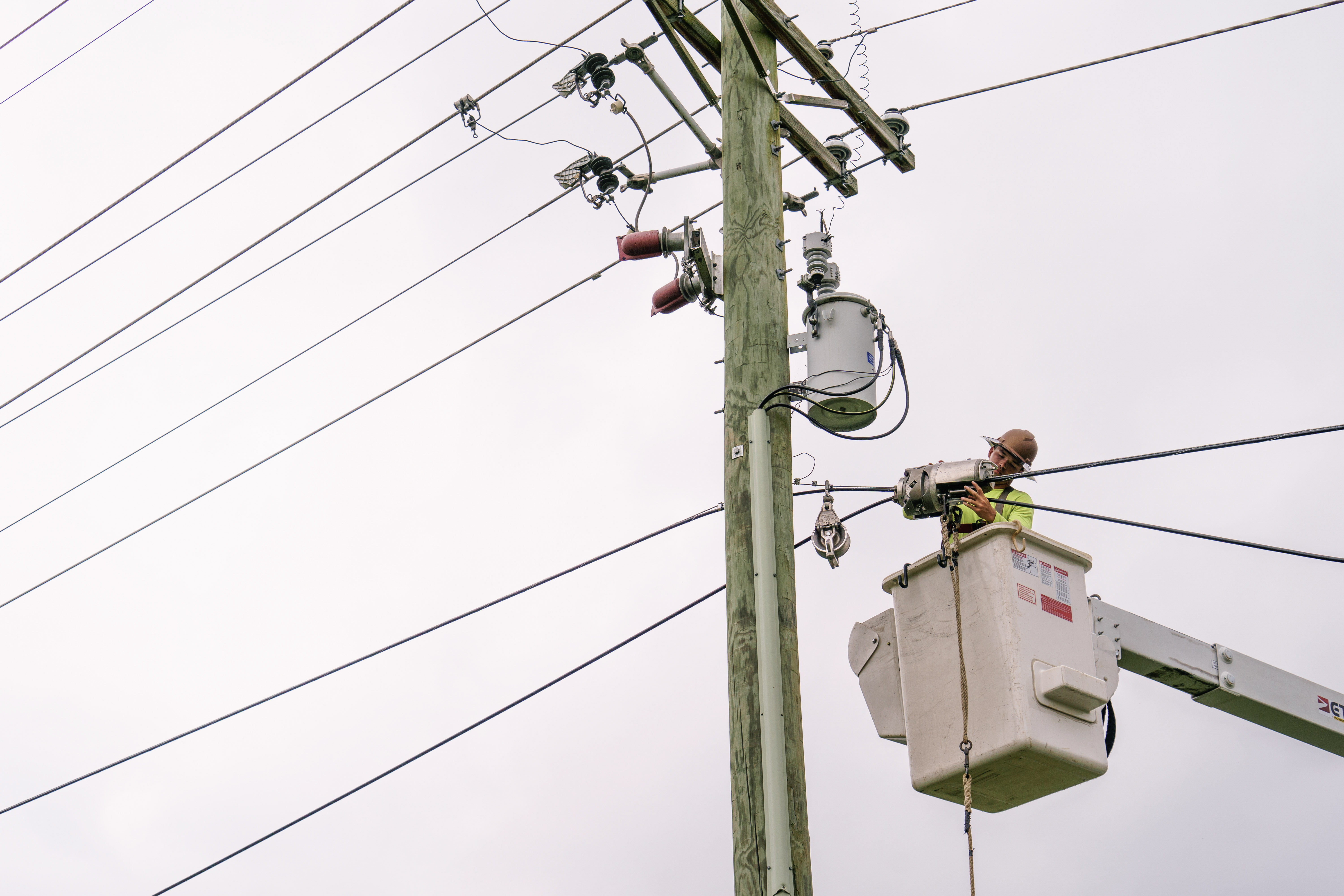 Utility worker in bucket truck repairing electrical lines
